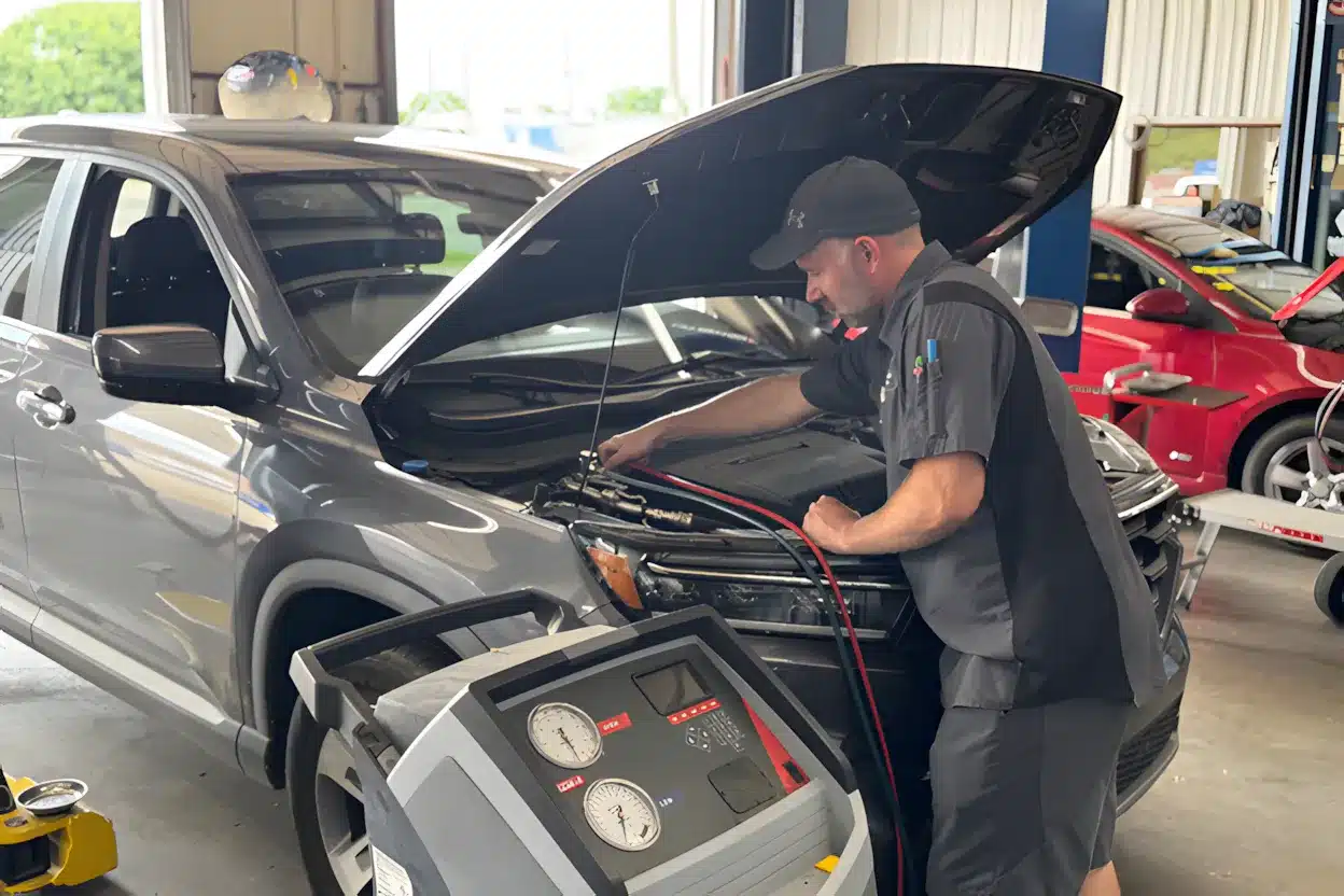 Automotive technician performing A/C service on a gray SUV using a diagnostic machine at Miller Brothers Automotive.
