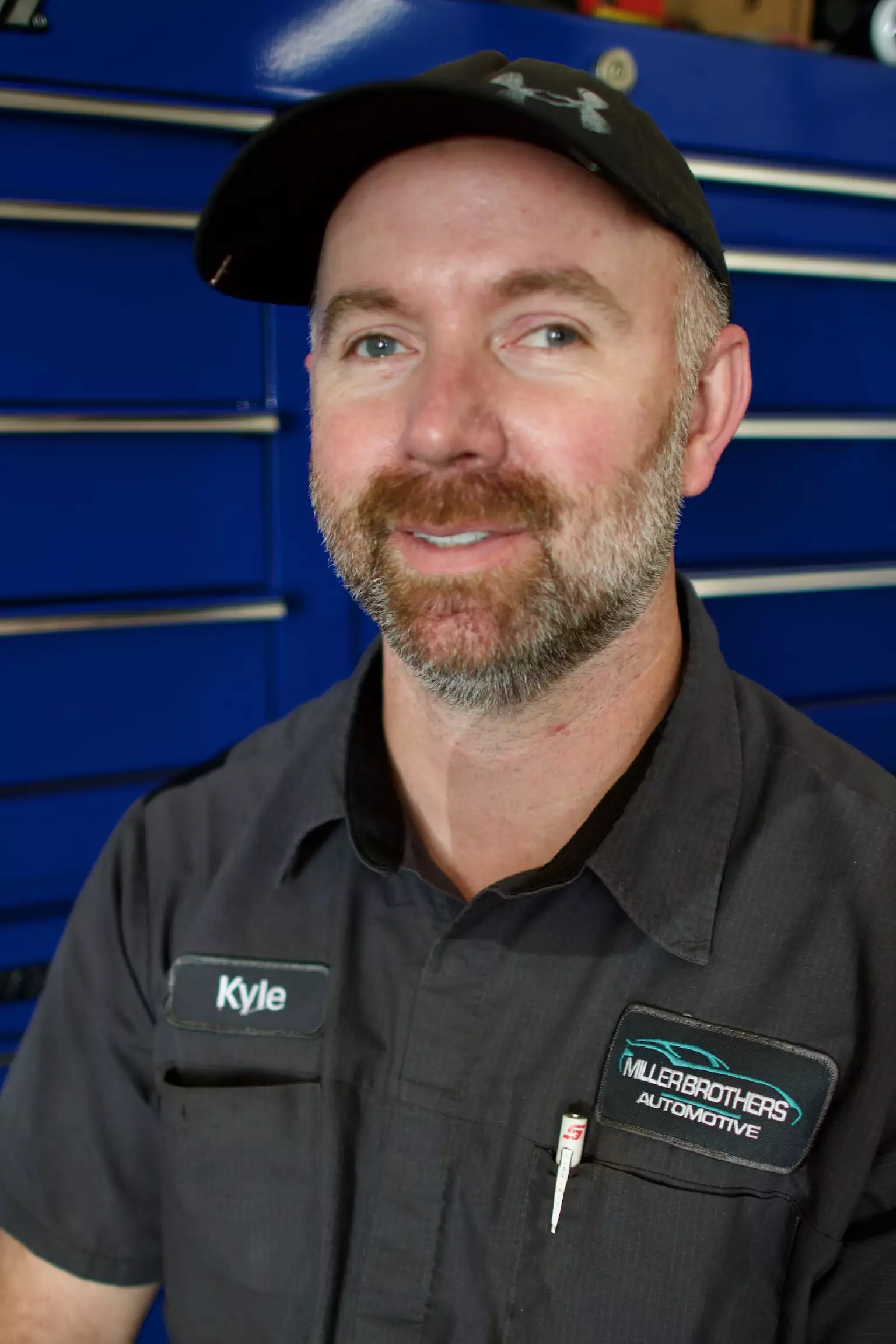 Kyle, Automotive Technician at Miller Brothers Automotive, in uniform in front of blue tool drawers in the workshop. Automotive Technician In Tecumseh OK at Miller Brothers Automotive