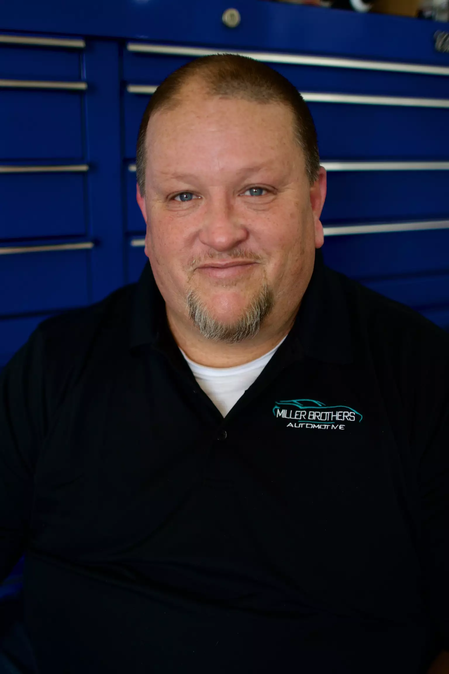 Nathan, Service Advisor at Miller Brothers Automotive, smiles in the garage office, wearing branded uniform and headset. Auto Repair Advisor In Tecumseh OK at Miller Brothers Automotive