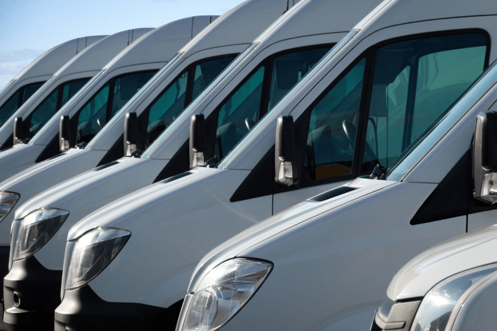 Fleet Maintenance in Tecumseh, OK, at Miller Brothers Automotive. A neat row of white commercial cargo vans parked side-by-side, representing vehicles managed during routine fleet maintenance services.