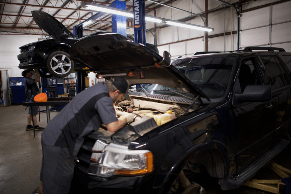 Pre-Purchase Inspection in Tecumseh, OK At Miller Brothers Automotive. Auto technician inspecting the engine bay of a SUV raised on a lift