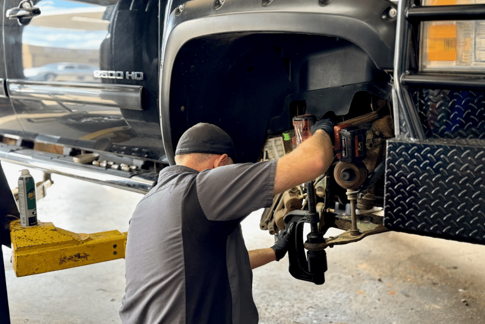 Suspension Repair, Auto Repair Services for Macomb, OK At Miller Brothers Automotive. Mechanic replacing front suspension components on a truck on a lift.
